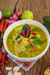 Green curry in a bowl with lime, red onion, lemon grass, garlic and kaffir lime leaves