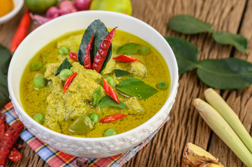 Green curry in a bowl with lime, red onion, lemon grass, garlic and kaffir lime leaves