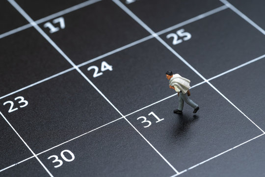 Business schedule plan, travel date or end of month pay day for salary man concept, miniature people businessman figure with suitcase walking on 31 end of month calendar