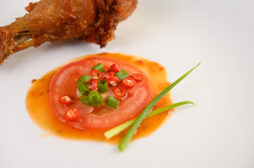 Fried chicken legs on a white plate with sauce.