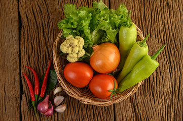Bell pepper, tomato, Onion, salad, chili, Shallot, garlic, cauliflower, and kaffir lime leaves on a wooden basket on wood table
