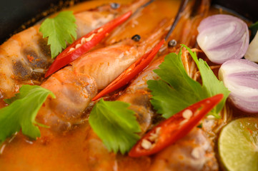 Obraz na płótnie Canvas Tom Yum Kung Thai hot spicy soup shrimp with lemon grass,lemon,galangal and chilli on wooden background Thailand Food