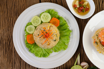Fried rice on a white plate on a wooden table.