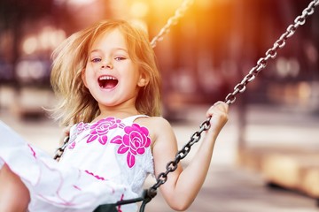 Little child blond girl having fun on a swing - obrazy, fototapety, plakaty