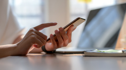 Close up view of college girl touching on smartphone in simple workplace