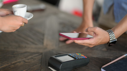 Cropped shot of customer using mobile payment in coffee shop