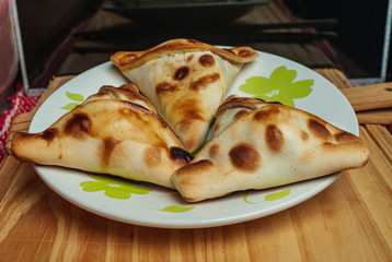Sfiha, kind of pie like originating in Syria and Lebanon and widely consumed in all the world, on white plate on rustic wooden table.