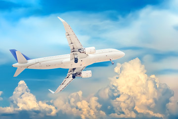 A white passenger plane that has just taken off against a background of beautiful and dramatic clouds. Extended landing gear