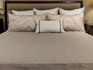 a cleanly made bed, topped with several small pillows