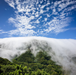 Obraz premium Amazing image of high moutnain peak covered with cluds on bright sunny day