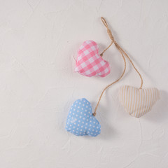 Hearts made of textile on a craft rope arranged together on a textured background. Valentine's day concept. Close-up. Square