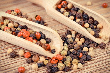Colored pepper with wooden scoop or spoon on wooden board. Cooking spice