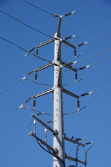 Low angle view of a complex electrical distribution pylon and wires under a deep blue sky