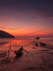 view seaside morning of fishing boats floating in the sea with red sun light in the sky background, sunrise at Mu Ko Phetra National Park, pak nam, la-ngu district, Satun, Thailand.