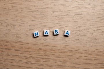 Word NASA in white cubes on light wooden background for your design templates