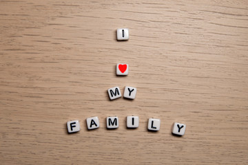 Word I LOVE MY FAMILY in white cubes on light wooden background for your design templates