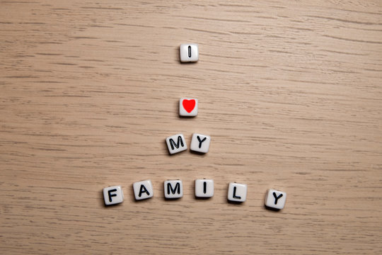 Word I LOVE MY FAMILY In White Cubes On Light Wooden Background For Your Design Templates