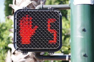 Pedestrian crosswalk traffic signal at a city intersection with a red hand warning to not enter...