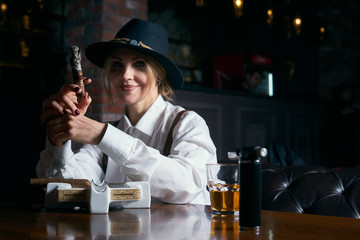 Senior attractive female gangster smoking cigar over dark background in restaurant
