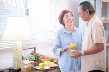 Asian elderly happy couple eating healthy food in the kitchen at home.retirement plan and old people concept