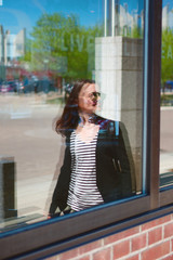 A young woman reflection in an inner city store front window 