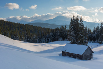 Charming snow-capped houses on a mountain Carpathian mountain valley, with magnificent views of peaks in winter.