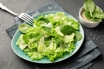 Healthy food. Top view of a fresh green vegetable salad of spinach, lettuce and sesame seeds on a plate.