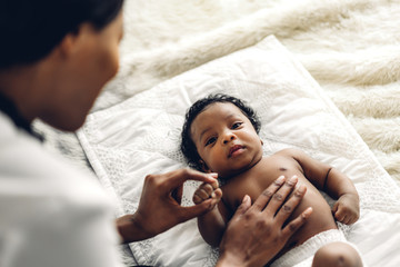 African american mother playing with adorable little african american baby in a white bedroom.Love...