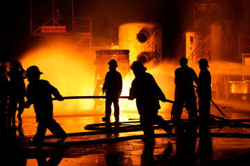 The Back side view of a group of firefighters helped stop the fire. Fire in the Industrial Factory...