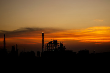 Fototapeta na wymiar Oil refinery or chemical plant silhouette with night lights on at sunset.