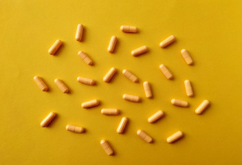 Yellow pills are scattered on a yellow background. Health and medicine concept.