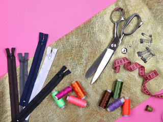 Set of tailoring tools and accessories on golden fabric. Top view, flat lay