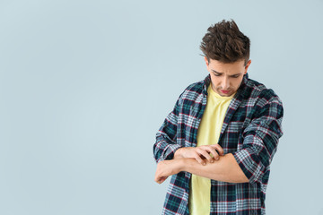 Scratching allergic man on light background