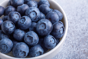 Fresh ripe and juicy blueberries in white bowl. Copy space. Macro photo
