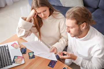 Worried young couple in debt at home