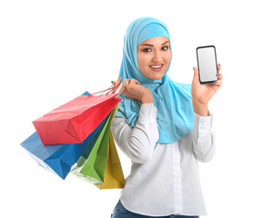 Young Arab woman with shopping bags and mobile phone on white background