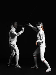 Fototapeta na wymiar Young fencers on dark background
