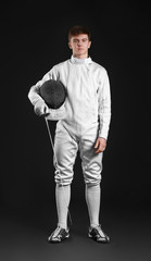 Young male fencer on dark background