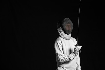 Young fencer on dark  background