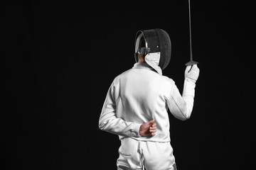 Young fencer on dark  background