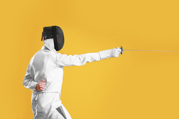 Young male fencer on color background