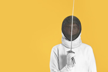Young male fencer on color background