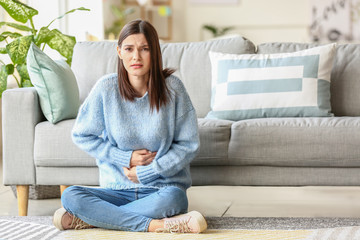 Young woman suffering from menstrual cramps at home