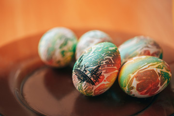 Woman paint eggs for Easter, paints draw black on a color egg.