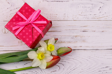 Gift box and bouquet of red tulips and daffodils on white wooden background. Concept of Valentine's Day, Women's Day, Mother's Day and Birthday. Top view, copy space