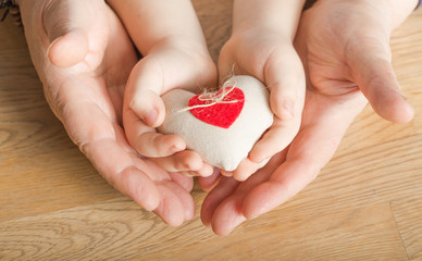 people, age, family, love and health care concept - close up of senior woman and little boy hands holding red heart over wooden background