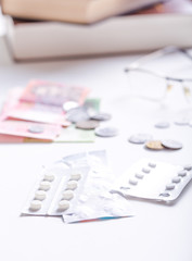 Fototapeta premium Medicine, finance, health care and drug trafficking - medical pills or drugs and coin on white background.