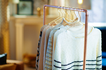 Closeup on copper clothes rack with clothes on hangers in room