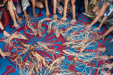 Different ages and nationalities females hands around their weaving craft on the carpet after the...