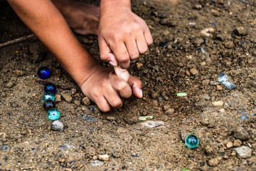 Child playing glass balls on the soil